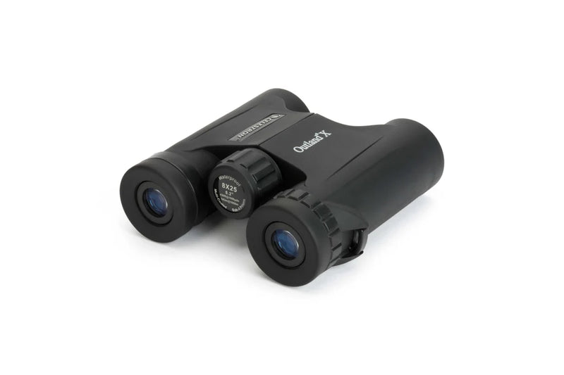 Celestron Outland X 8x25 roof binoculars showing the back view with focus wheel and eyepieces in a natural outdoor setting