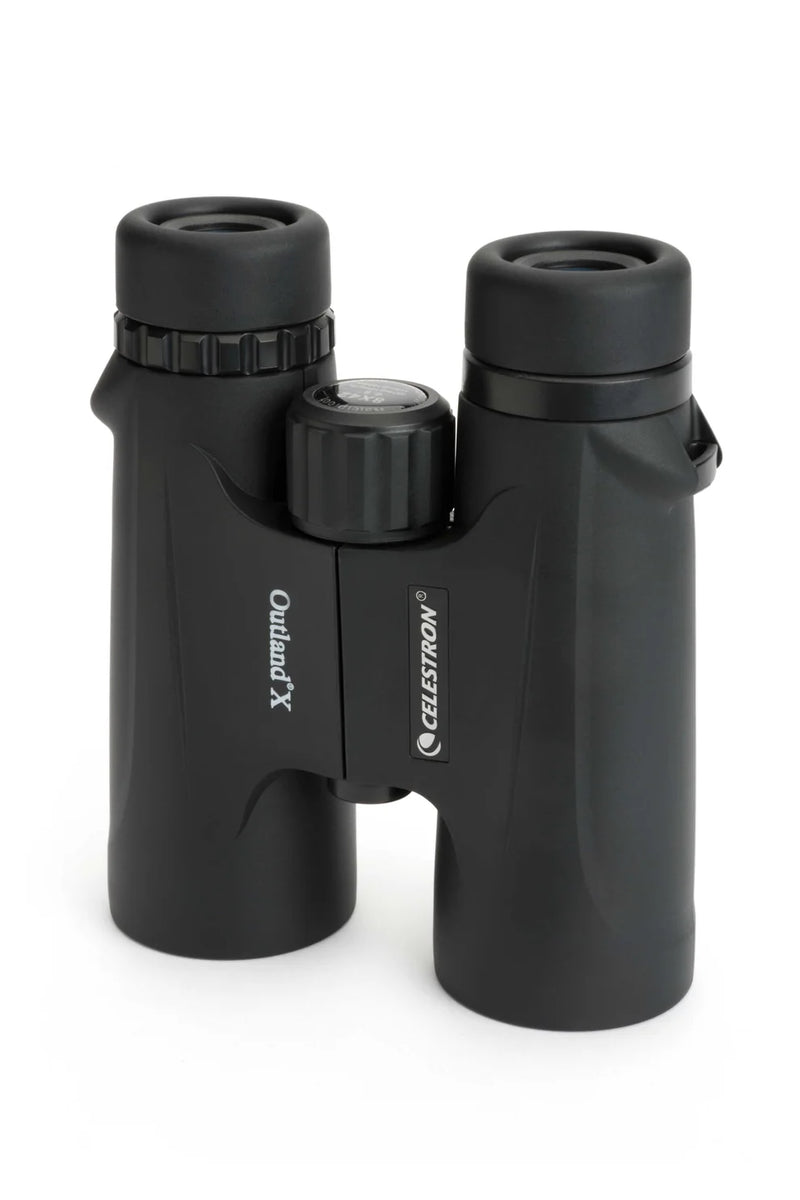 Celestron Outland X 8x42 roof binoculars showing the black body, eyepieces, and adjustable focus in a standing position.