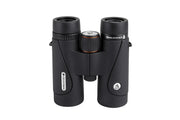 Celestron TrailSeeker ED 10x42 binoculars with black rubber armor, showing the eyepieces and focus wheel against a nature background.
