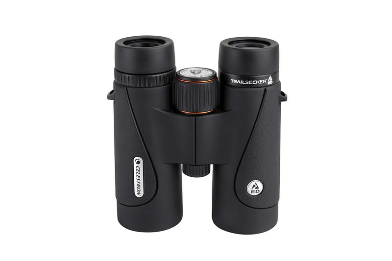 Celestron TrailSeeker ED 10x42 binoculars with black rubber armor, showing the eyepieces and focus wheel against a nature background.
